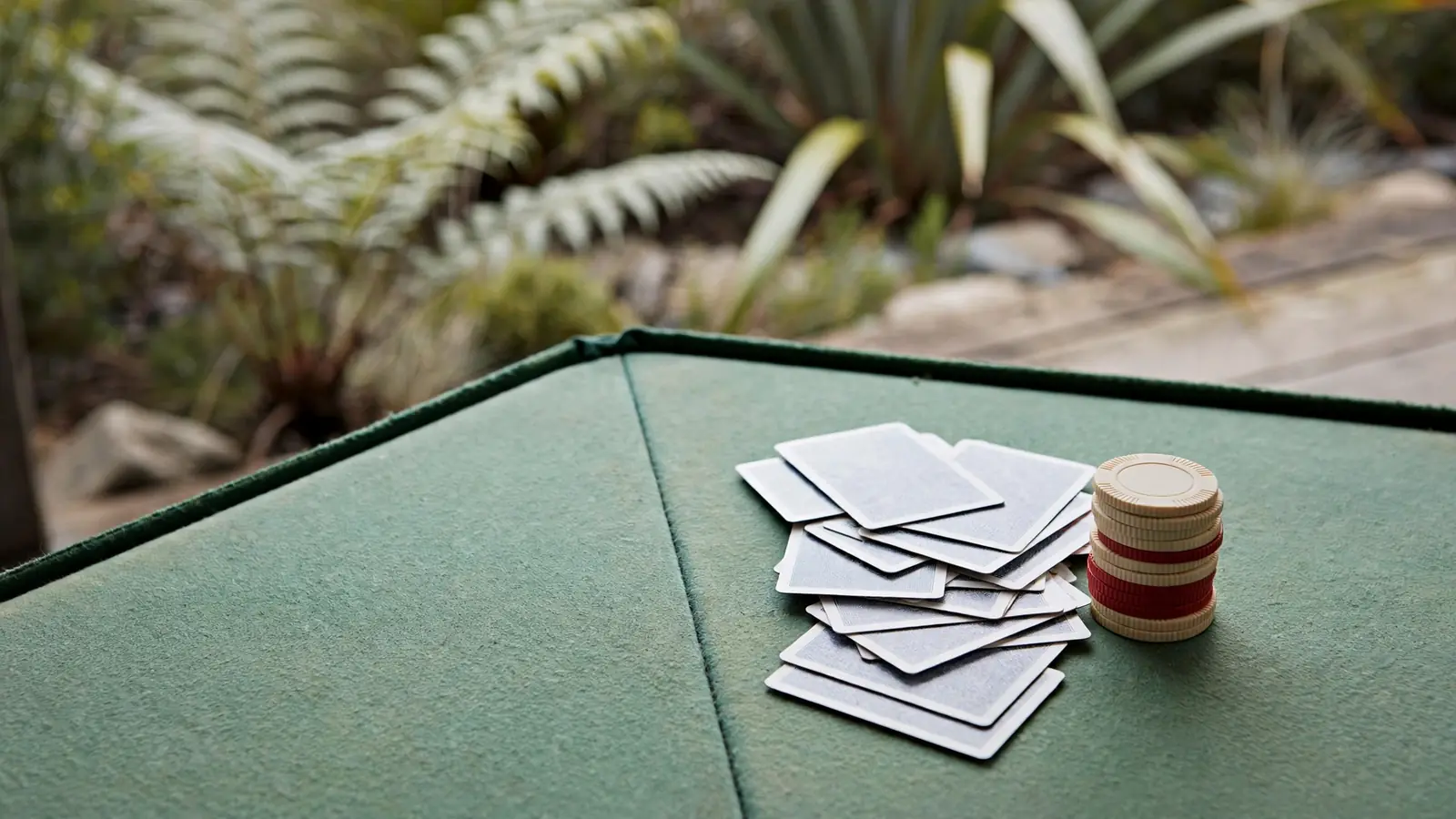 Stack of chips and a shuffled deck of cards on green felt.